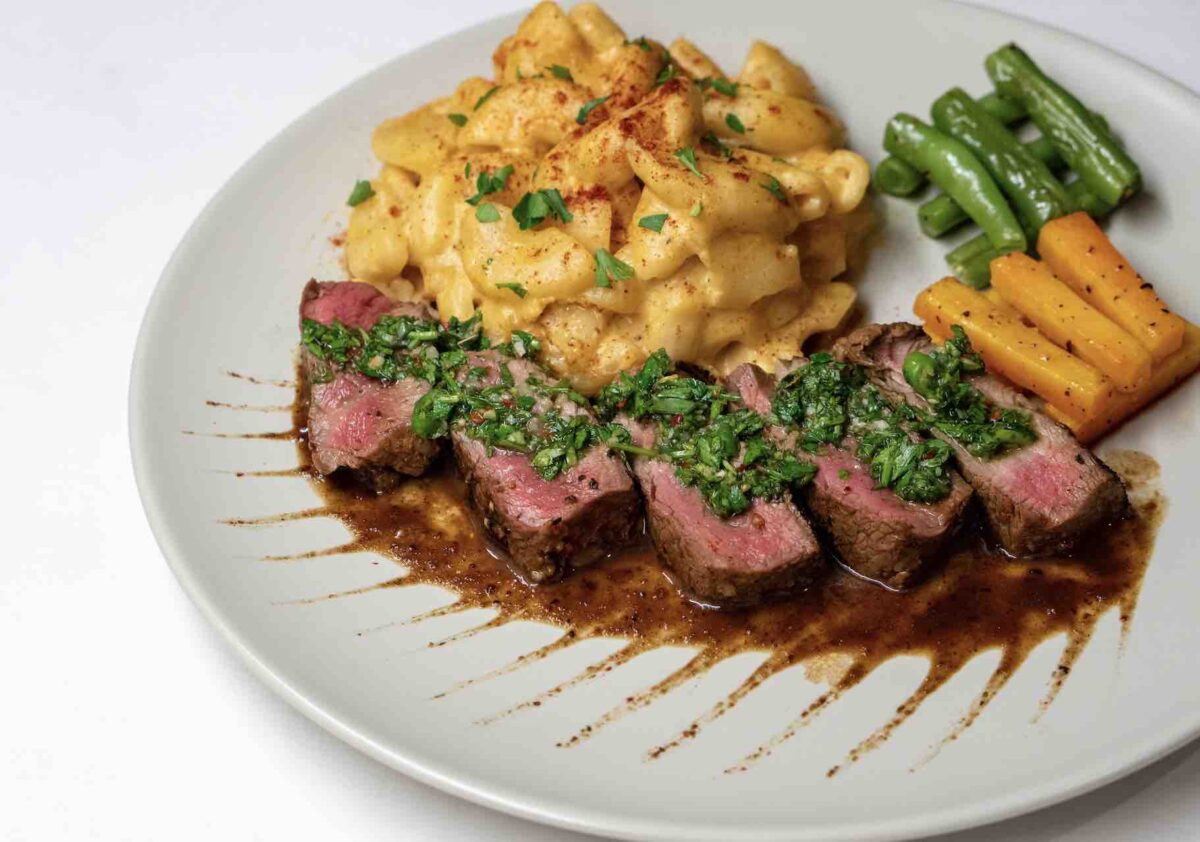 photograph of sliced steak with chimichurri sauce