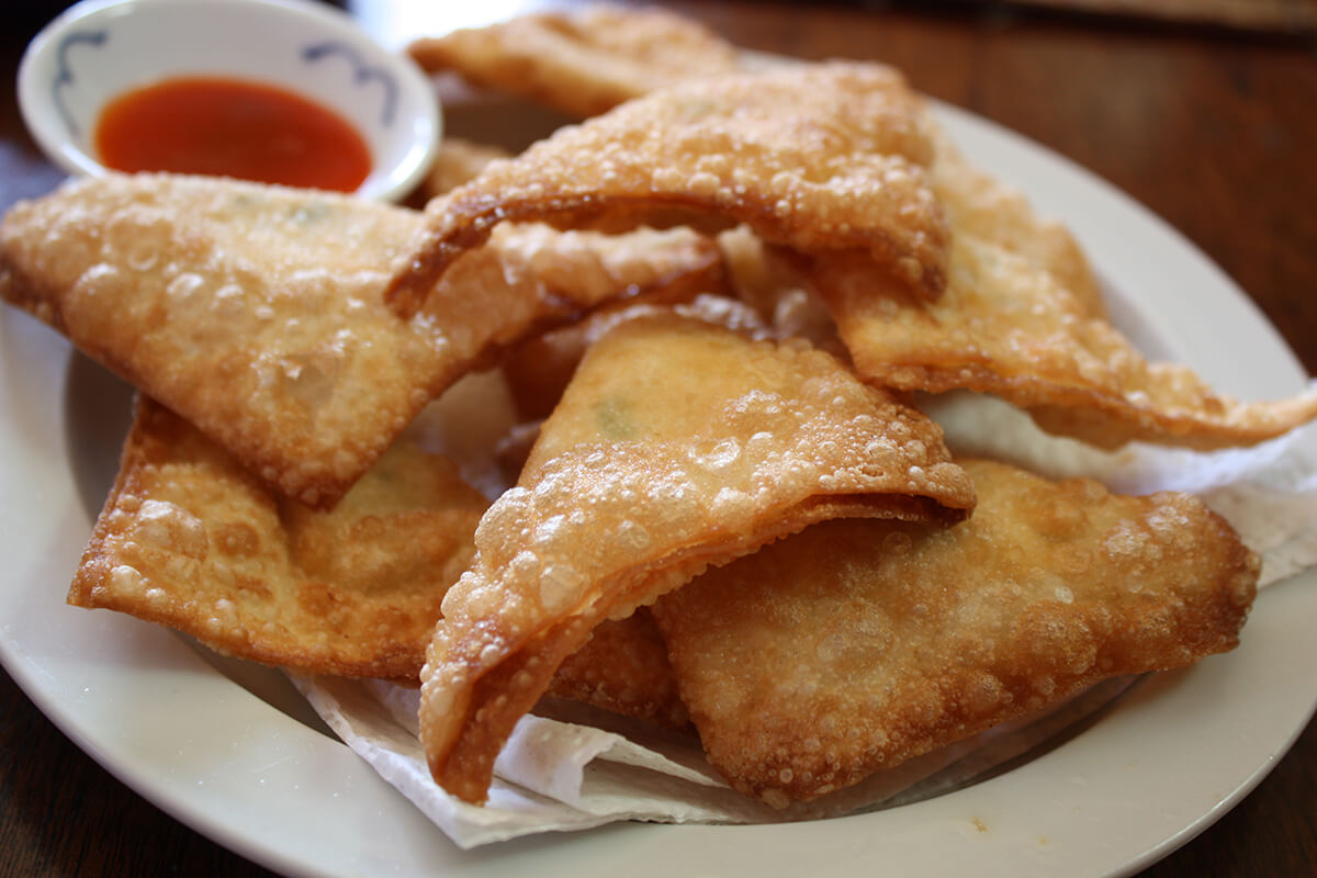 A plate of crab rangoon and sauce.